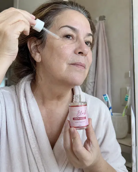 Mulher madura de cabelo grisalho aplicando sérum no rosto antes do protetor solar